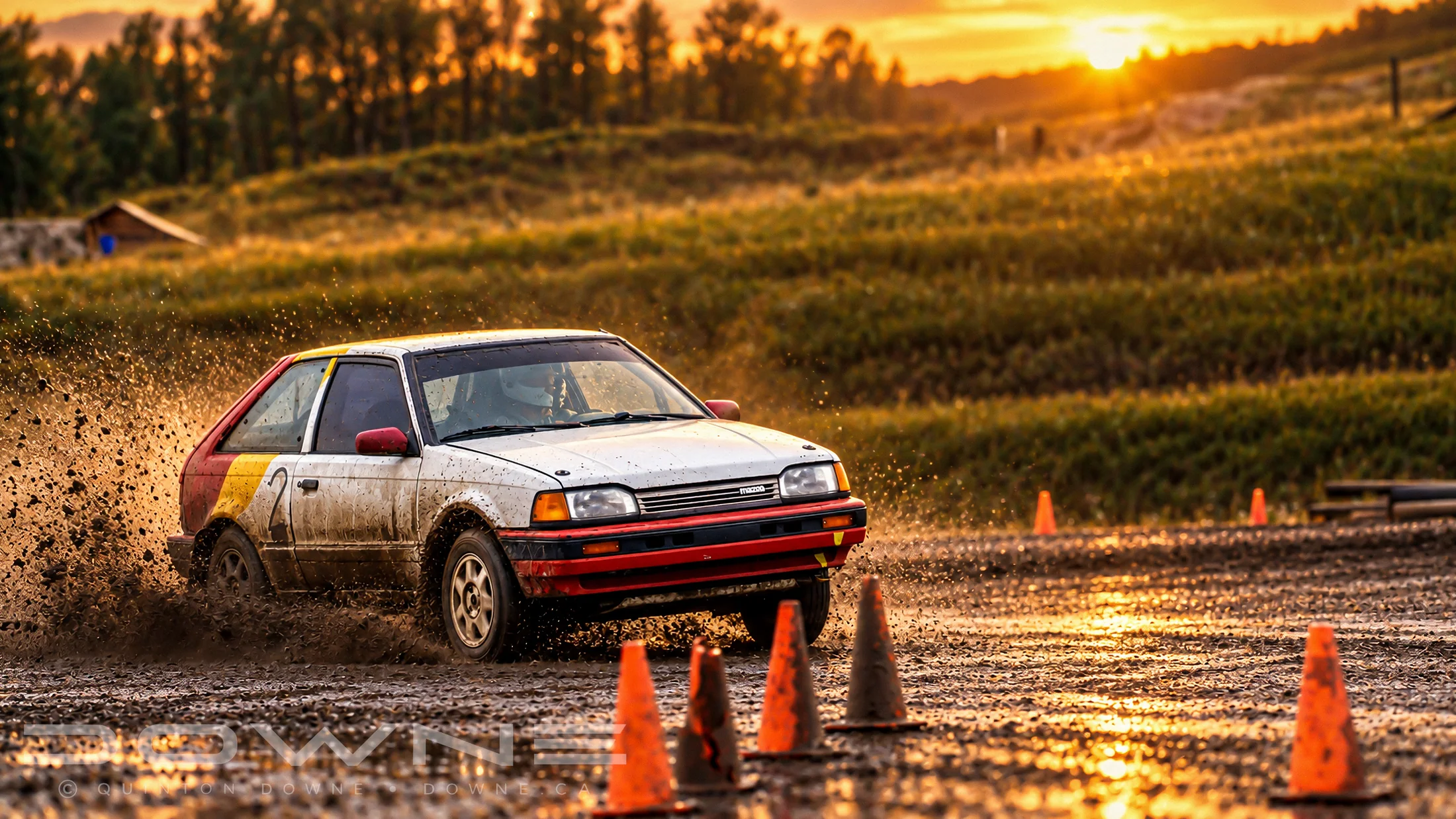 White rallycross hatchback throwing dirt through a corner — photograph by QDowne